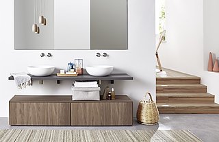 Badezimmer mit zwei weißen, runden Waschbecken auf einer grauen Konsole und Holzschrank.