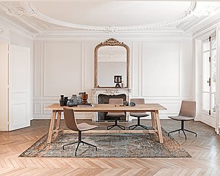 Ein langer Holztisch in einem eleganten Altbau-Esszimmer mit Stuckdecke und Kamin.