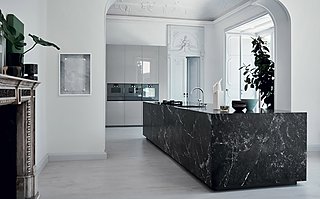 Eine große Kücheninsel aus schwarzem Marmor in einer Altbauwohnung mit Stuckdecke.