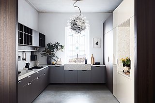 Eine U-förmige Küche mit dunklen Holzschränken und einem großen, verzierten Spülbecken unter einem Fenster.