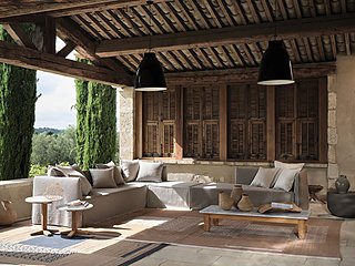 Eine große, L-förmige Couch auf einer überdachten Terrasse mit Holzbalken.