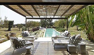 Eine große Lounge-Garnitur auf einer Terrasse mit Blick auf einen Pool und eine weite Landschaft.