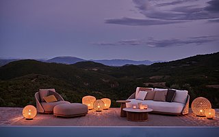 Eine Lounge-Garnitur mit Korb-Sesseln bei Dämmerung am Pool.