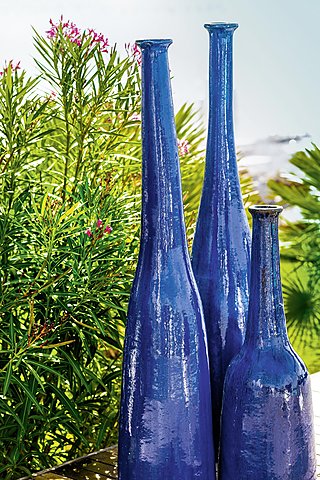 Drei hohe, blaue Vasen auf einer Holzoberfläche im Freien.