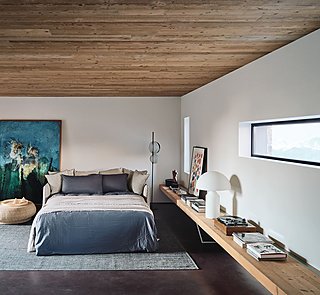 Ein modernes Schlafsofa mit grauer Bettwäsche in einem Raum mit Holzdecke.