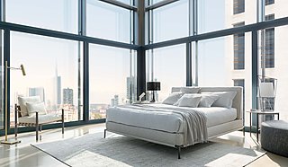 Ein graues Bett in einem Penthouse-Schlafzimmer mit Blick auf eine Stadt.