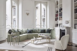 Ein modernes, grünes Ecksofa in einem hellen Wohnzimmer im Altbau mit Stuckdecke.