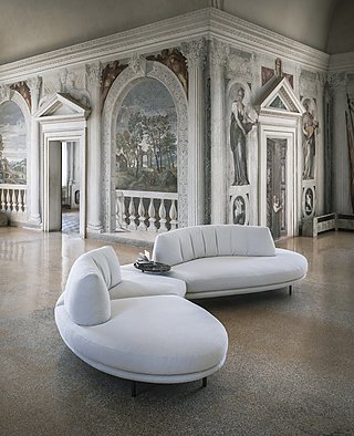 Zwei geschwungene, weiße Sofas in einem prunkvollen Raum mit Wandmalereien.