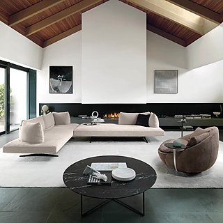 Eine moderne Wohnlandschaft mit einem schwarzen Marmortisch vor einem Kamin.