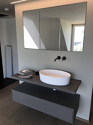 Schwebender Waschtisch mit ovalem Aufsatzbecken, schwarzer Wandarmatur und Spiegelschrank.