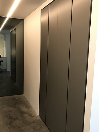 Raumhoher Einbauschrank in dunklem Grau im Flur mit indirekter Deckenbeleuchtung.