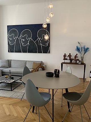 Runder Esstisch mit grauen Schalenstühlen, Glaspendelleuchten und großem Kunstwerk an der Wand.