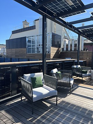 Loungemöbel mit weißen Polstern und grünen Kissen auf der Dachterrasse.