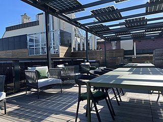 Gesamtansicht der Dachterrasse mit Loungemöbeln, Stehtischen und Solarpergola.