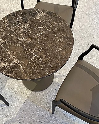 Runder Kaffeetisch aus Naturstein mit dunkler Marmorplatte und Lederstühlen von oben.