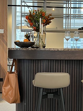 Bardetail mit Blumenstrauß, Obstschale und Weingläsern auf der Steinplatte.