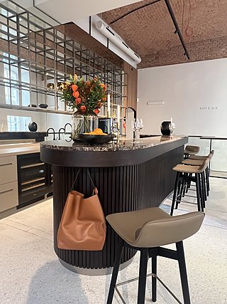 Gesamtblick auf das Mitarbeitercafé mit Bar, Barhockern und Ziegeldecke.