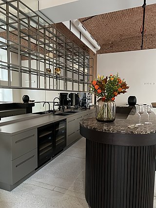 Blick auf Bar und Küchenzeile mit Spiegelregal, Weinkühlschrank und Ziegelgewölbe.