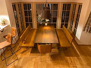 Esstisch mit Lederbänken und Barhocker von der Galerie aus, Sprossenfenster im Hintergrund.