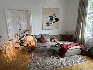 Wohnzimmer mit Sofa, Kugelleuchte am Boden, Palme und Flügeltür im Altbau mit Fischgrätparkett.