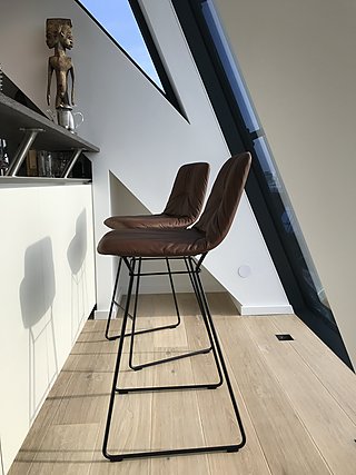 Zwei braune Lederbarhocker an der Küchentheke neben der Dachschräge.