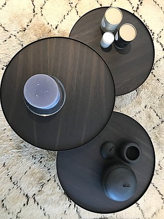 Drei runde Beistelltische aus dunklem Holz auf einem hellen Berberteppich von oben.