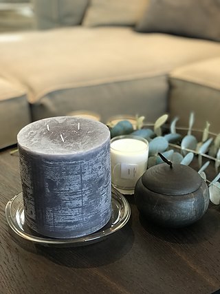 Dekorative Kerzen und Eukalyptuszweig auf einem dunklen Beistelltisch.