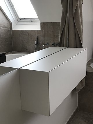 Badezimmer mit weißer Badewannenverkleidung, Natursteinfliesen und Dachfenster.