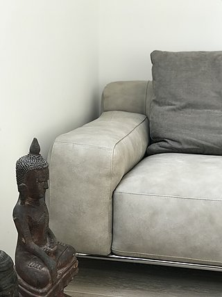 Graues Ledersofa mit Buddha-Figur als Dekoration daneben.
